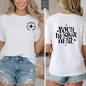 Puede incluir: Una camiseta blanca de manga corta con texto y gráficos en negro. El pecho delantero izquierdo muestra un logotipo circular con el texto YOUR DESIGN HERE y una estrella. La parte posterior presenta el texto grande YOUR DESIGN HERE con estrellas y corazones.