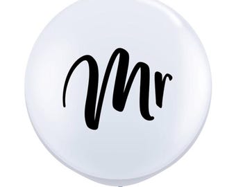 May include: White balloon with the word "Mr." printed in black cursive lettering.