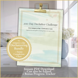 May include: A clipboard with a gold clip holds a decluttering guide. The guide is titled "200-Day Declutter Challenge" and includes the text "One Category a Day - 15 Minutes or Less." A circular sticker reads "15 minutes a day Decluttering Bundle + bonus Completion Chart."