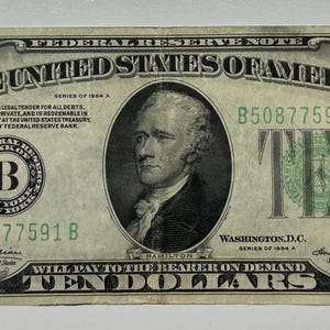 May include: A United States ten-dollar bill featuring a portrait of Alexander Hamilton. The bill displays the text "THE UNITED STATES OF AMERICA" and "TEN DOLLARS". The bill is primarily green and black.