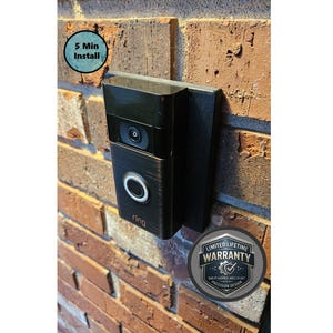 May include: A black and bronze Ring video doorbell mounted on a brick wall. The doorbell has a camera, a circular button, and the brand name "ring" is visible. The text "5 Min Install" and "Limited Lifetime Warranty" are also present.