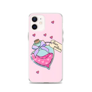 May include: A pink iPhone case with a clear back and a cute illustration of a heart-shaped bottle with a purple ribbon and a tag that says "love potion". There are small pink hearts scattered around the bottle.
