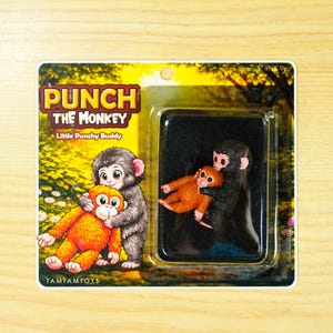 Figura de resina hecha a mano inspirada en Punch the Monkey, con embalaje de cartón.