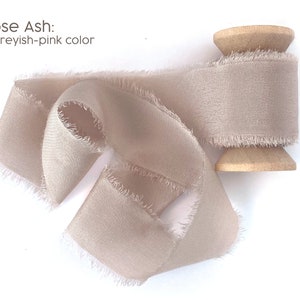 May include: A spool of dusty rose silk ribbon with frayed edges. The ribbon is a pale, greyish-pink color.  Rose Ash: A greyish-pink color.