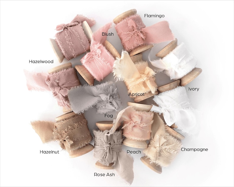 Peut inclure: Collection de bobines de rubans d&eacute;coratifs de diff&eacute;rentes couleurs, dont rose, beige et gris. Chaque bobine est &eacute;tiquet&eacute;e avec un nom de couleur, comme "Hazelwood", "Blush" et "Fog". Les rubans ont un bord effiloch&eacute;, ajoutant une touche rustique.