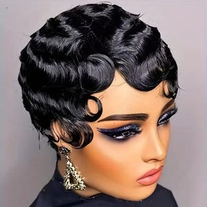 May include: A woman with dark skin and a short, black, wavy hairstyle. She is wearing dramatic eye makeup with dark blue eyeshadow and a gold triangular earring. The woman is looking to the side.