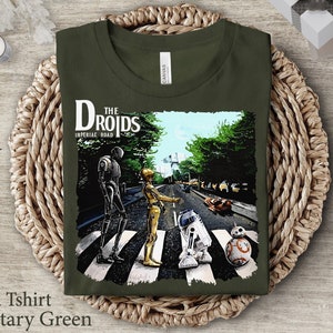 May include: A green t-shirt with a graphic of Star Wars characters walking across a crosswalk. The text "The Droids" and "Imperial Road" is printed on the shirt.