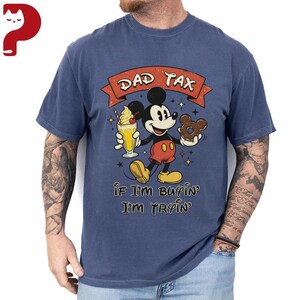Puede incluir: Camiseta azul con un dise&ntilde;o de Mickey Mouse de dibujos animados. Mickey sostiene una bebida y una rosquilla. El texto "DAD TAX" est&aacute; encima de Mickey, y "IF I'M BUYIN' I'M TRYIN'" est&aacute; debajo. La camiseta tiene un aspecto vintage.