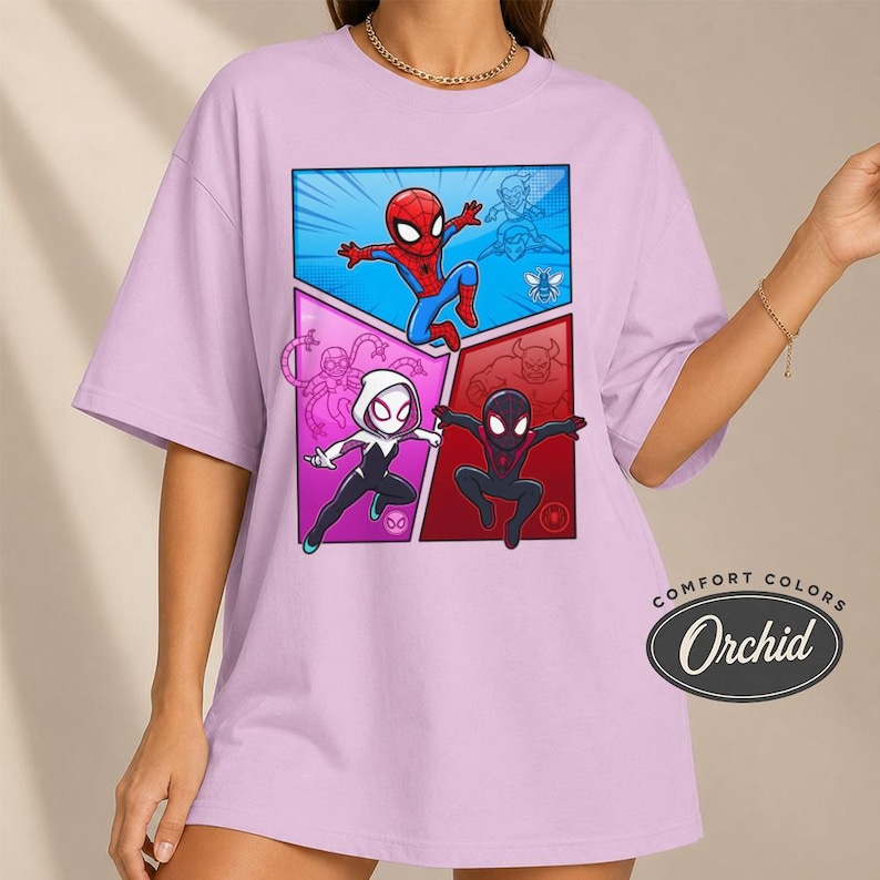May include: A light purple t-shirt featuring a comic book style graphic of Spider-Man and two other Spider-Verse characters. The graphic is divided into three sections with a blue, pink, and red background. The shirt has the words "COMFORT COLORS" and "Orchid" printed on the bottom right.