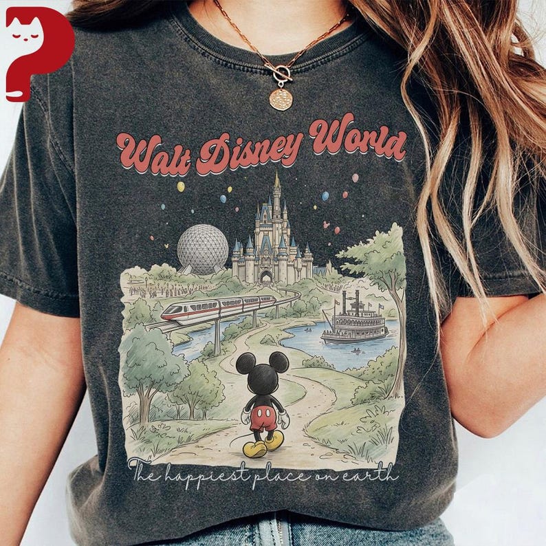 May include: Dark gray t-shirt featuring a colorful illustration of Walt Disney World. The design includes the park's castle, a monorail, and Mickey Mouse. The text "Walt Disney World" and "The happiest place on earth" are also visible.