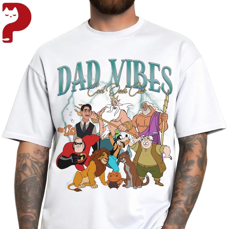 Peut inclure: T-shirt blanc avec un motif de personnages de dessins anim&eacute;s et le texte "DAD VIBES Cool Dads Club" en bleu sarcelle et blanc. Le motif comprend des personnages de divers films d'animation.