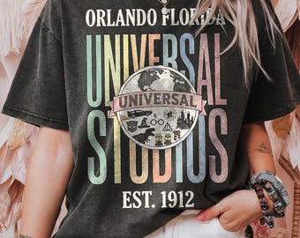 May include: Black t-shirt with the text "ORLANDO FLORIDA UNIVERSAL STUDIOS EST. 1912". The design includes a globe and various Universal Studios icons in a colorful, vintage style.