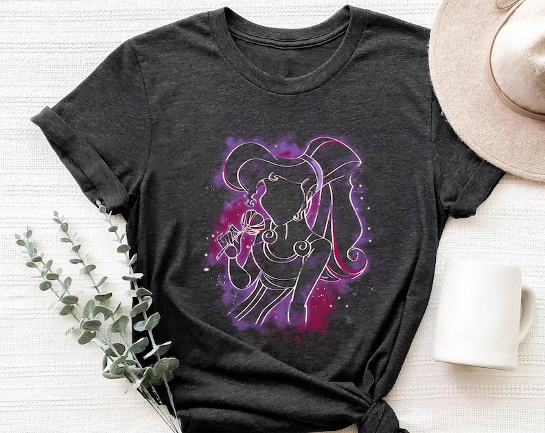 May include: A dark grey t-shirt with a purple and pink silhouette of a woman with long hair holding a flower. The woman is surrounded by a purple and pink nebula.