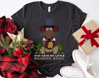 May include: A dark gray t-shirt with a cartoon rat wearing a top hat and scarf. The rat is surrounded by holly and the text "God Save My Little Broken Body" is printed below the rat.