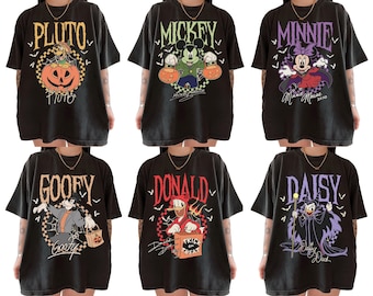 May include: Six black t-shirts featuring Disney characters in Halloween-themed designs. Each shirt displays a different character's name in a unique font, along with related graphics. Characters include Pluto, Mickey, Minnie, Goofy, Donald, and Daisy.