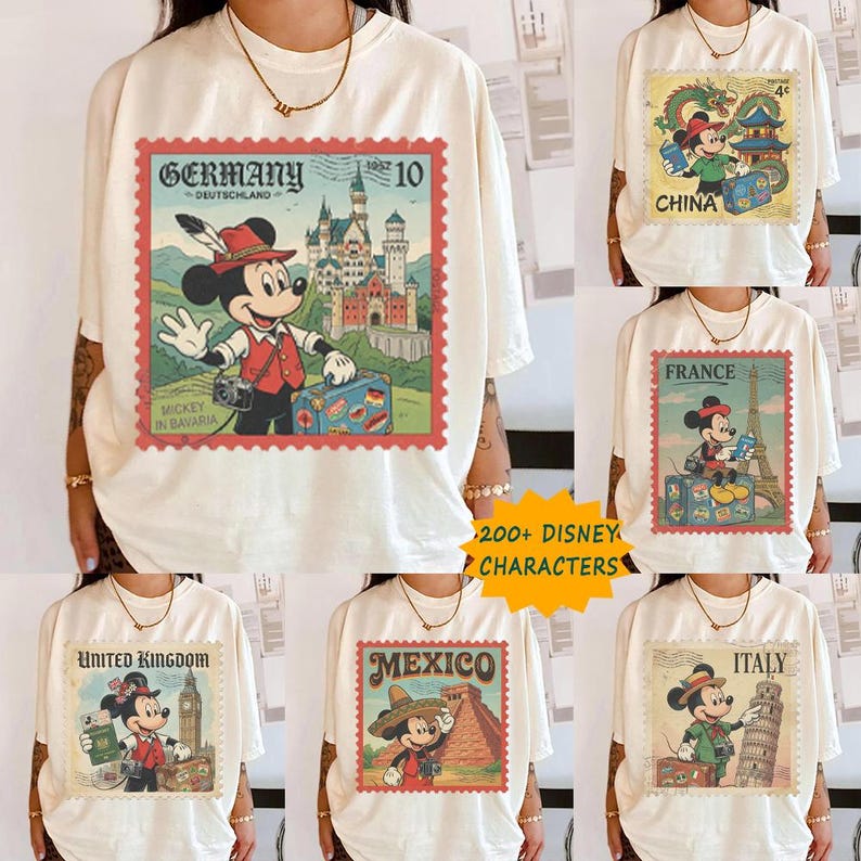Op de afbeelding: Cr&egrave;mekleurige T-shirts met Mickey Mouse-ontwerpen met reisthema. Elk shirt toont een postzegel uit verschillende landen: Duitsland, China, Frankrijk, Verenigd Koninkrijk, Mexico en Itali&euml;. De shirts hebben de tekst "200+ DISNEY CHARACTERS".