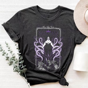 May include: A dark gray t-shirt with a graphic print of Ursula, the sea witch from Disney's The Little Mermaid. The graphic features Ursula with tentacles and the text "The Sea Witch".