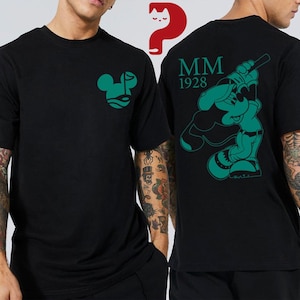 May include: Black t-shirt with a green graphic of a mouse-like character on the front and back. The front graphic is a stylized face. The back graphic shows the character playing baseball, with "MM 1928" above it.