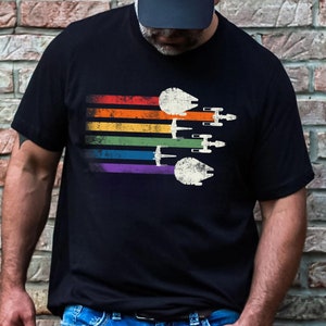 May include: A black t-shirt featuring a rainbow stripe design and a vintage-style image of Star Wars spaceships flying in formation.