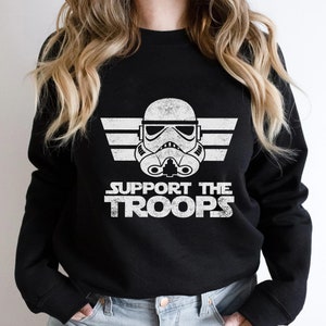 May include: Black sweatshirt with a white graphic of a Star Wars Stormtrooper helmet with the text "SUPPORT THE TROOPS" underneath.
