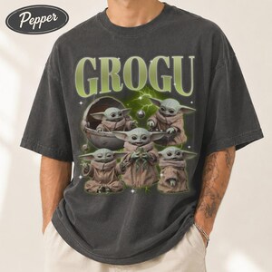 May include: Dark gray t-shirt featuring the word "GROGU" in green, with a graphic of Grogu from The Mandalorian. The graphic shows Grogu in various poses, with a green and white lightning bolt design in the background.