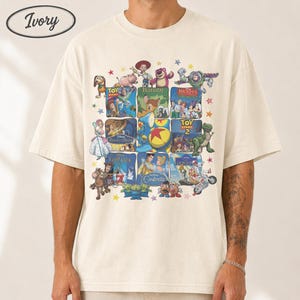May include: Ivory-colored t-shirt featuring a collage of Disney movie posters. The design includes characters from Toy Story, Bambi, Beauty and the Beast, and Cinderella. The shirt has a crew neck and short sleeves, with the word "Ivory" in an oval on the top left.
