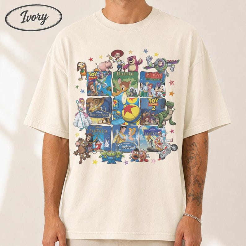 May include: Ivory-colored t-shirt featuring a collage of Disney movie posters. The design includes characters from Toy Story, Bambi, Beauty and the Beast, and Cinderella. The shirt has a crew neck and short sleeves, with the word "Ivory" in an oval on the top left.