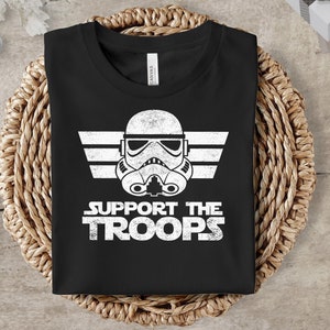 May include: Black t-shirt with a white graphic of a Star Wars Stormtrooper helmet with wings and the text "Support the Troops".