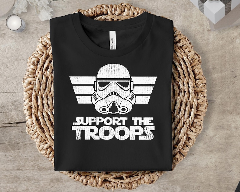 May include: Black t-shirt with a white graphic of a Star Wars Stormtrooper helmet with wings and the text "Support the Troops".