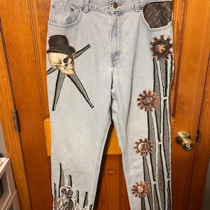 May include: A white ceramic mug with a black handle and the text "But First, Coffee" in a bold, black font. The mug is set against a neutral background, highlighting its simple design.