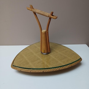 May include: A triangular wicker serving tray with a woven handle. The tray has a glass top and a woven base.