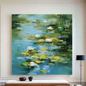 以下が含まれることがあります： スイレンのある池の風景を描いた油絵。 ターコイズブルーの水面、白と黄色のスイレンの葉と花が特徴です。 明るくモダンな部屋に飾られており、木製のベンチと黒いランプがあります。