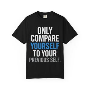May include: Black t-shirt with the text "ONLY COMPARE YOURSELF TO YOUR PREVIOUS SELF" in white, blue, and gray lettering. The shirt has short sleeves and a crew neck. The shirt is displayed on a white background.