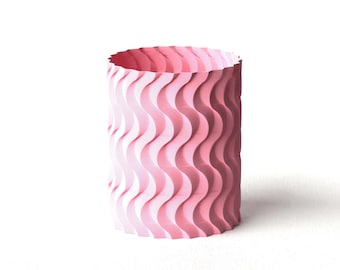 May include: A cylindrical, pink vase with a wavy, textured pattern. The vase is a light shade of pink, with a darker pink interior. The design features vertical, undulating lines that create a sense of movement and depth. The vase is suitable for home decor.