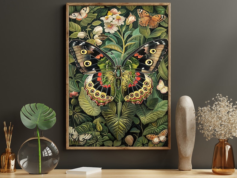Op de afbeelding: Een ingelijste print van een grote, kleurrijke vlinder met zwarte, groene, gele en rode vleugels. De vlinder wordt omringd door groene bladeren en witte bloemen.