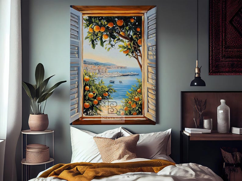 Op de afbeelding: Olieverfschilderij van een kustlandschap gezien door een raam met blauwe luiken. Sinaasappelbomen omlijsten het uitzicht op de zee, boten en gebouwen. Het kunstwerk hangt boven een bed met wit beddengoed en een gouden deken.