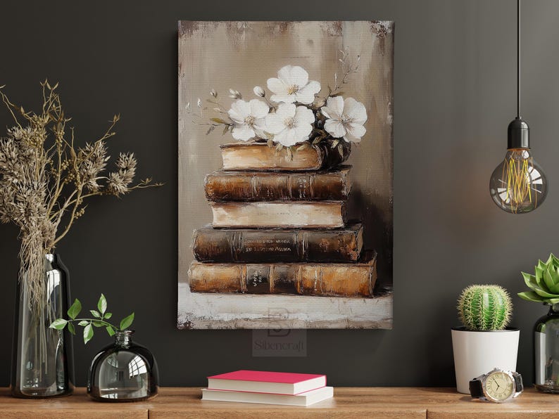 May include: An oil painting depicts a stack of antique books topped with white flowers. The books are various sizes and shades of brown, with visible titles. The artwork is displayed on a dark wall, with decorative elements like vases and a cactus.