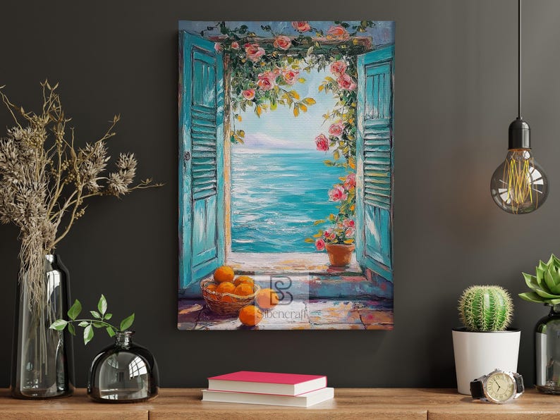 May include: A canvas print shows a coastal scene through turquoise shutters with pink roses. A basket of oranges sits on the windowsill. The artwork evokes a Mediterranean aesthetic, with a bright blue sea and sky.