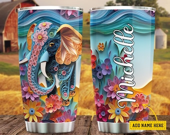 May include: A stainless steel tumbler with a colorful paper-cut design of an elephant and flowers. The tumbler has a blue background with a yellow and orange accent. The text "Michelle" is on the side of the tumbler.