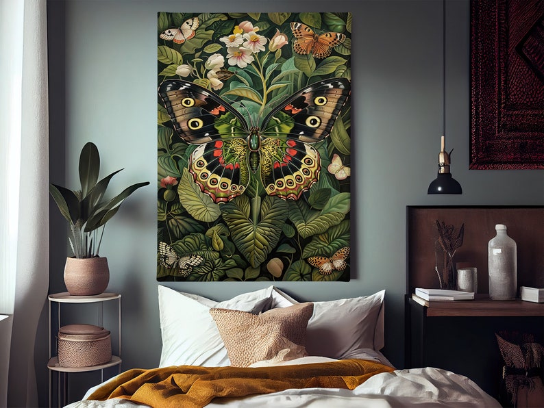 Op de afbeelding: Een grote, kleurrijke vlinder met zwarte, rode, gele en groene vleugels is omringd door weelderig groen en witte bloemen. De vlinder is het middelpunt van de afbeelding, met zijn vleugels wijd uitgespreid.