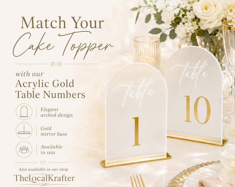 May include: Two acrylic gold table numbers with arched design. The numbers are white with gold accents and bases. The text on the signs reads "Table 1" and "Table 10". The signs are displayed on a table with flowers and a candle.