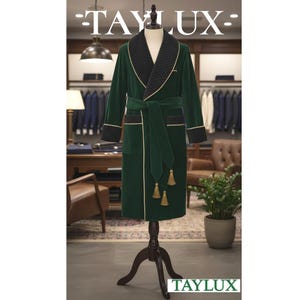 May include: A green velvet robe with black quilted lapels, cuffs, and a matching belt. Gold trim accents the edges and cuffs. The robe has a tie belt with gold tassels. The Taylux logo is visible at the top and bottom of the image.