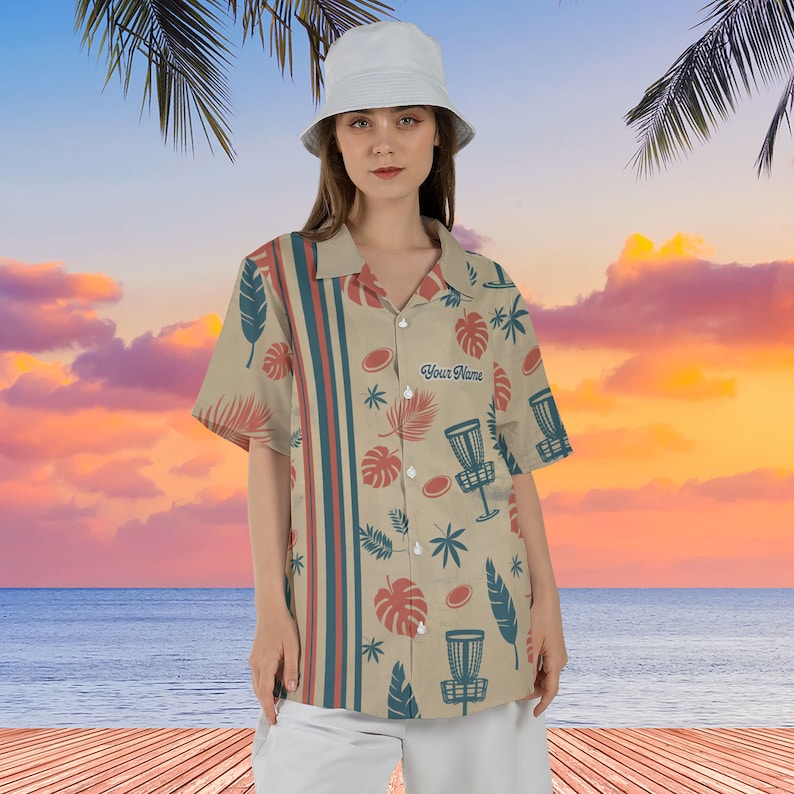 May include: A beige button-up shirt with a tropical print featuring palm leaves, disc golf discs, and the text "Your Name".