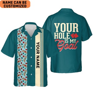 May include: A teal blue Hawaiian shirt with a white and yellow vertical stripe on the left side. The stripe has the text "YOUR NAME" printed on it. The right side of the shirt has a pattern of miniature cornhole boards. The back of the shirt has the text "YOUR HOLE IS MY GOAL" printed in red and white.