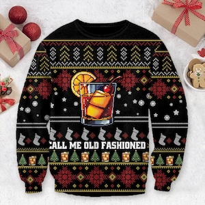 Op de afbeelding: Zwarte kersttrui met een gepixeld Old Fashioned cocktailontwerp. De trui heeft een cocktailglas met ijsblokjes, een sinaasappelschijfje en een kers. De tekst "CALL ME OLD FASHIONED" staat eronder.