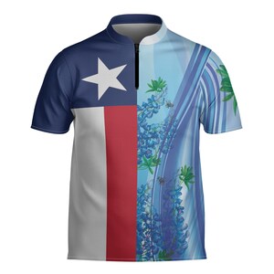 May include: Short-sleeved polo shirt with the Texas state flag on the left and a floral pattern with bluebonnets on the right. The shirt has a navy blue collar and a quarter-zip closure.