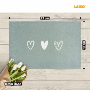 May include: A light blue doormat with three white heart designs. The doormat measures 75 cm wide by 50 cm long and is 8 mm thick.