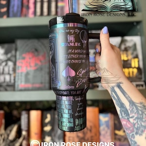 May include: Black and teal Stanley tumbler with a handle and straw. The tumbler features text and graphics, including the words "You're my toy" and "Spade Broke". The design includes a spade symbol and the Stanley logo.