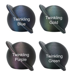 May include: Four small, round, black, iridescent planets with a silver ring around the middle. Each planet has a different color: blue, gold, purple, and green. The text "Twinkling" is written on each planet, followed by the color name.