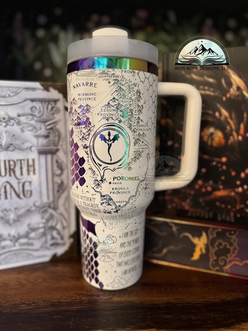 May include: White travel mug with a purple and white dragon design. The mug features a map of a fictional land with the words "Navarre", "Morraine Province", "Elsum Province", "Brae Province", "Poromiel", "Pavis", "Krovla Province", and "Cordyn". The mug also has the text "I am the storm and the fury of every story that has ever been written".
